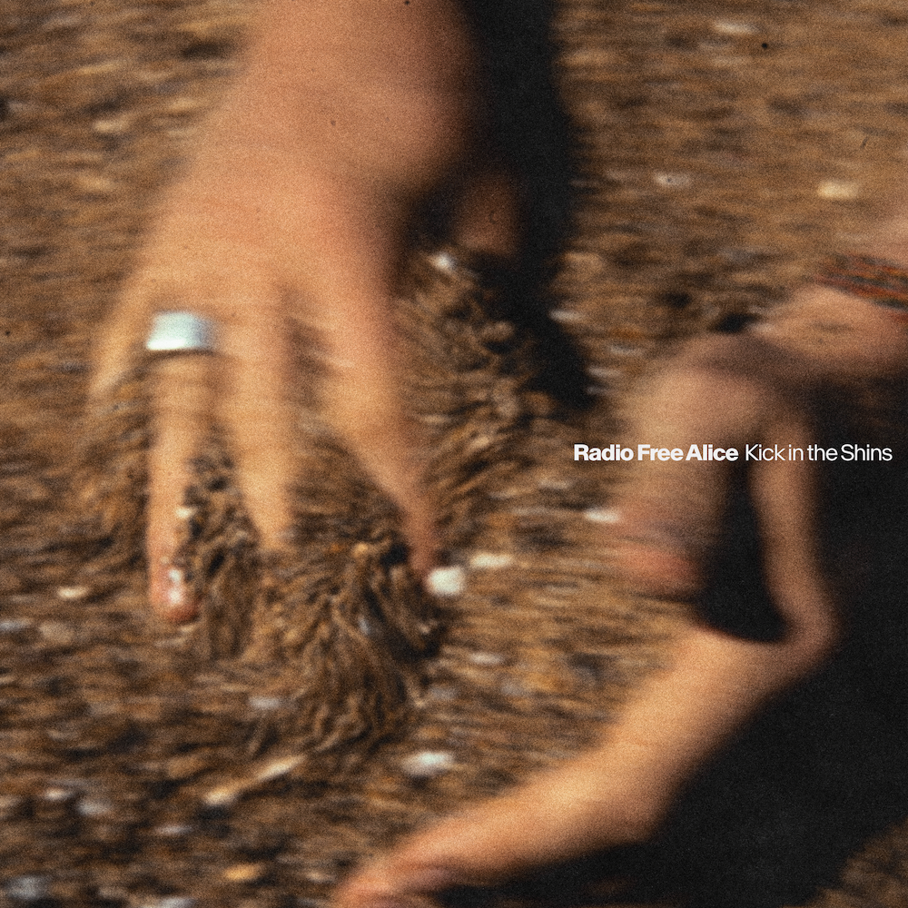 Album cover artwork for Kick in the Shins by Radio Free Alice featuring a motion-blurred close-up of hands in sand.